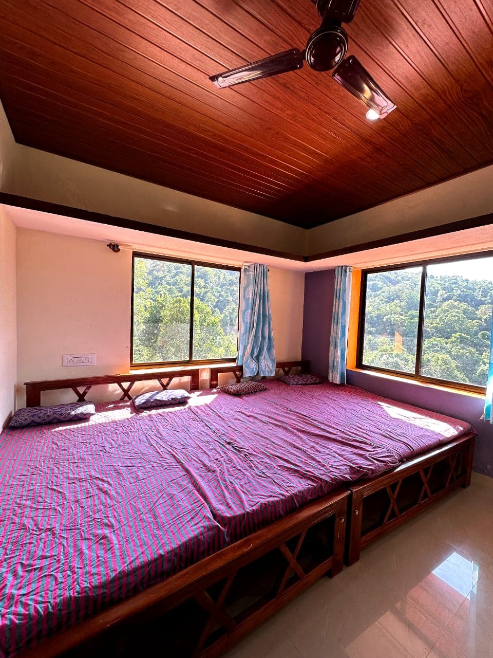 Spacious room with joined beds and windows opening to the Western Ghats at Mullodi homestay